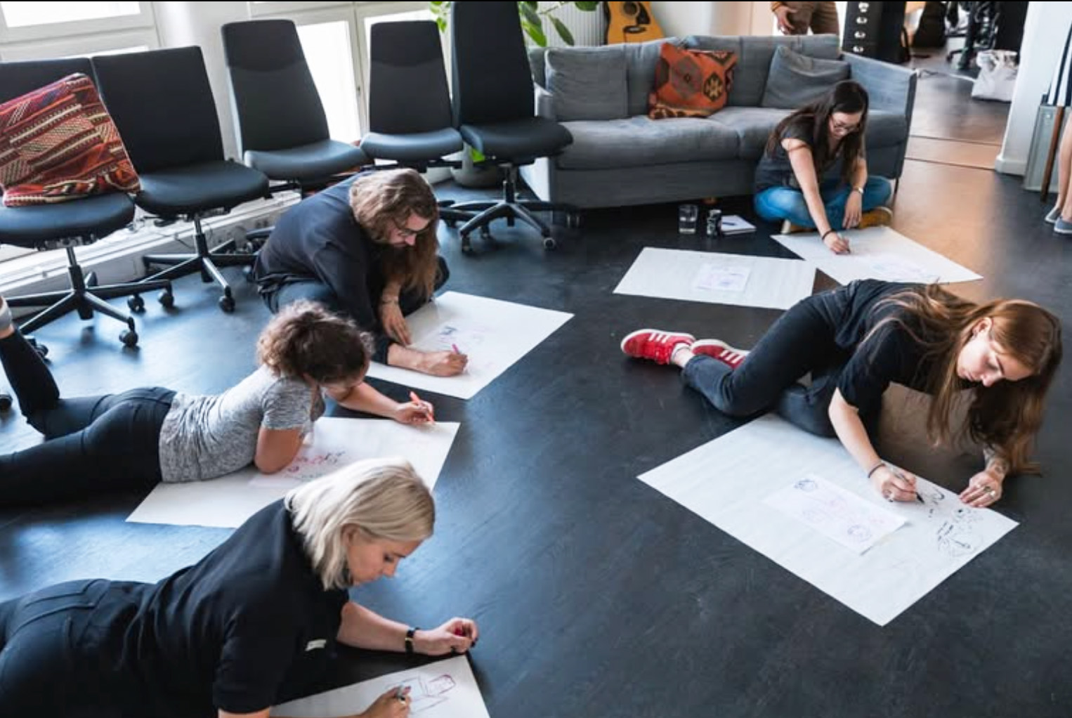 Participants lying on the floor drawing on large sheets of paper